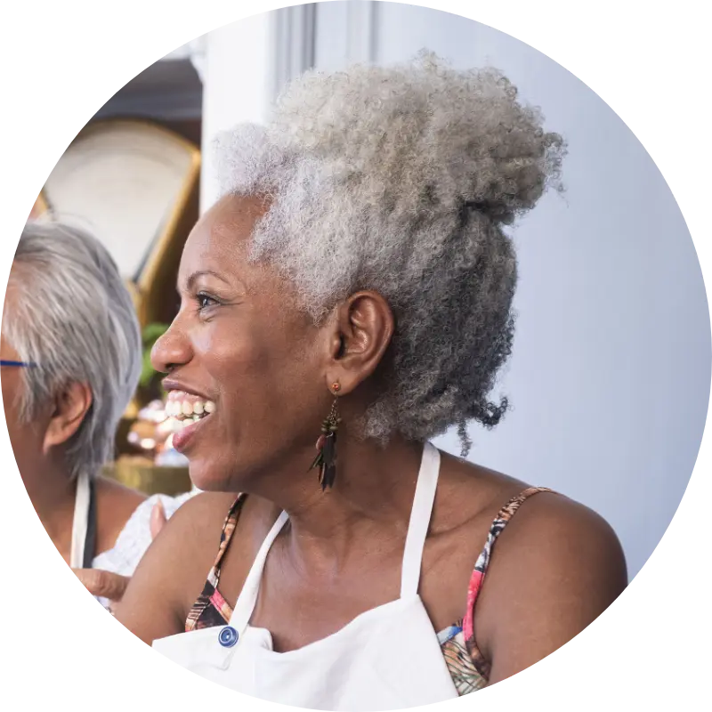 Side profile photo of older woman smiling while among a group of acquaintences.